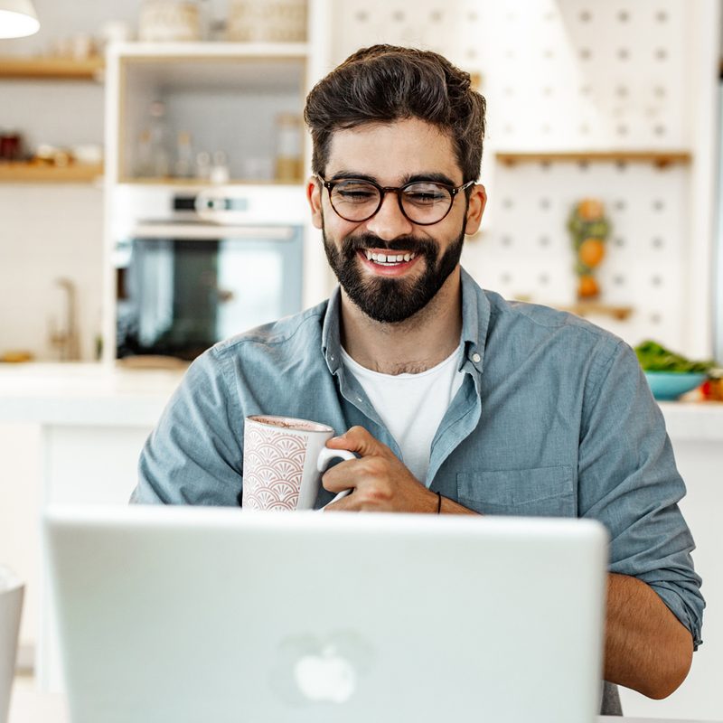 A man with mug using a laptop.