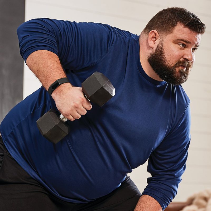 An overweight man uses a dumbbell to lose weight