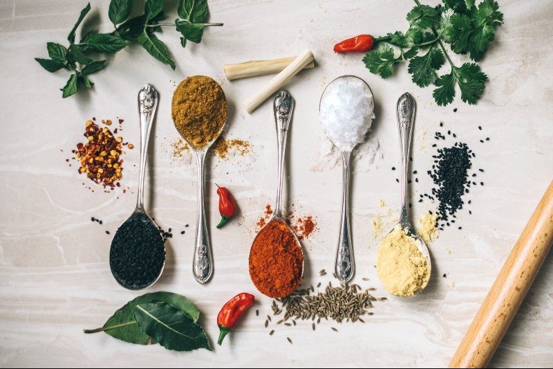 fresh herbs and dried spices on a counter.