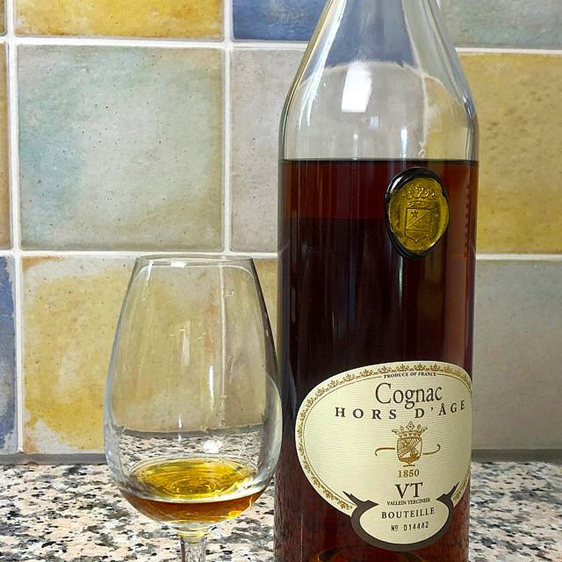 A bottle of Vallein Tercinier Hors d'Age beside a nearly-empty glass of cognac.