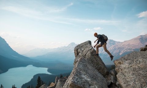 A man walking towards a rocky point overlooking a lake
