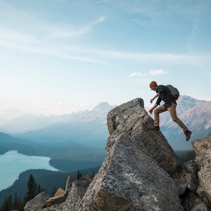 A man walking towards a rocky point overlooking a lake