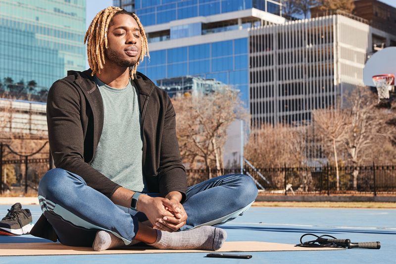 A man with Fitbit tracker meditating in the city.
