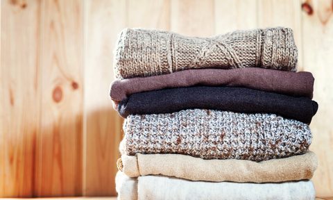 Knit cozy sweater folded in a pile on wooden background