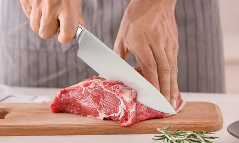 Chef knife used to cut a juicy steak.