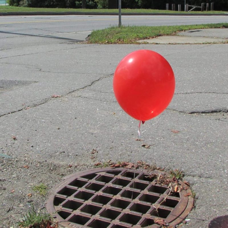A sewer drain along Jackson & Union with a red balloon tied to it.