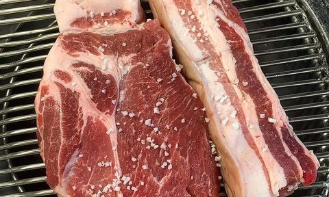 Jeju black pig shoulder and belly cuts on a grill.