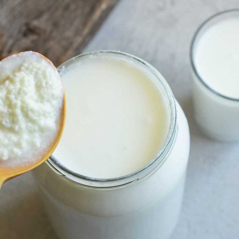 A spoonful of kefir and two glasses of kefir on a table