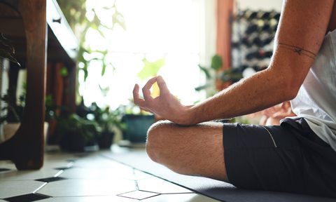 Shot of a man meditating in the lotus position at home.