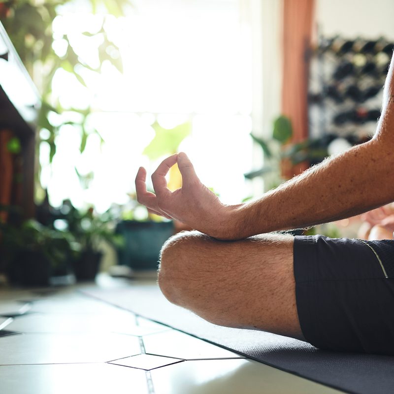 Shot of a man meditating in the lotus position at home.