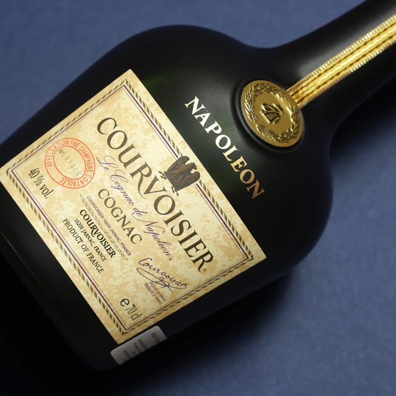 A bottle of Courvoisier Napoleon Cognac on a blue table.