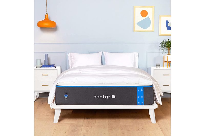 A Nectar memory foam mattress sits on a bed frame in a furnished bedroom.