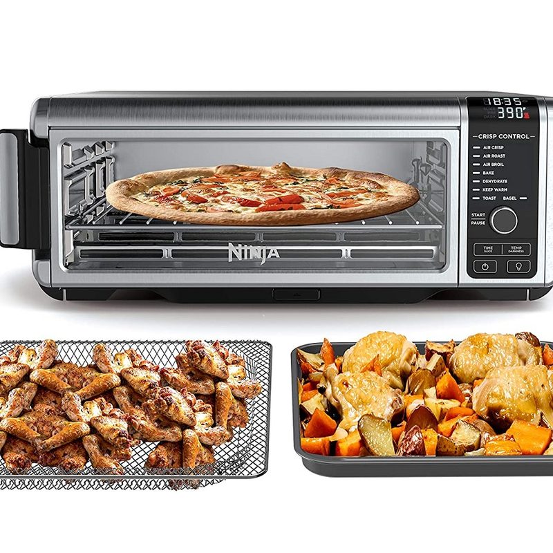 The Ninja Foodi Digital Air Fry Oven with pizza inside and cooked meals outside.