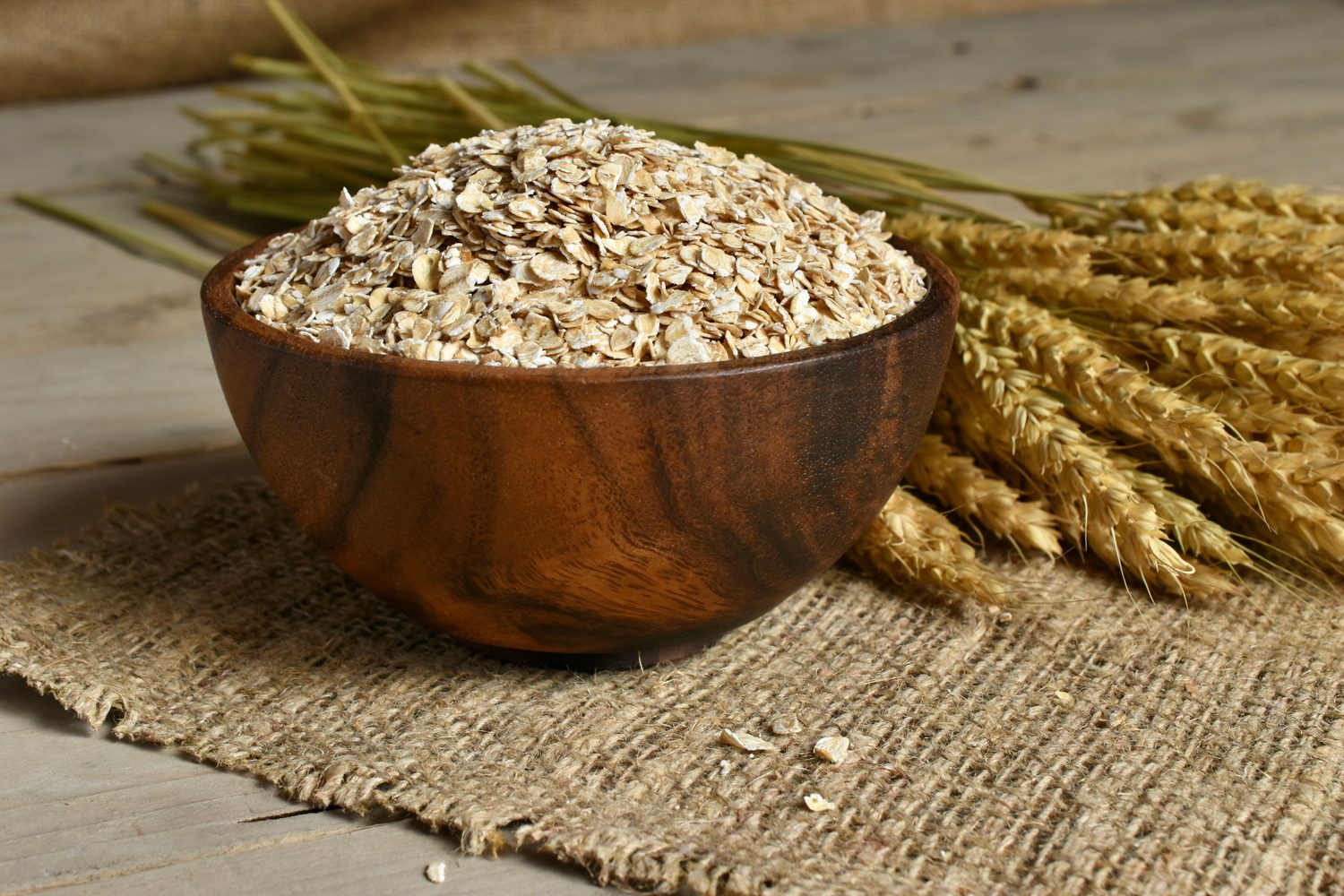 Bowl of oats and oat stalk on cloth.