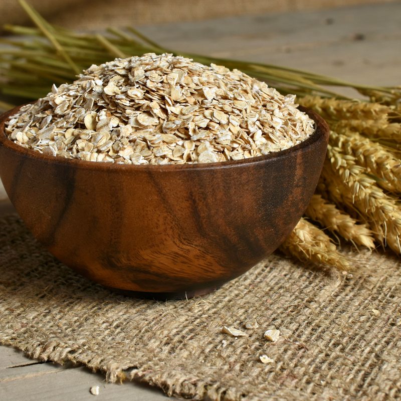 Bowl of oats and oat stalk on cloth