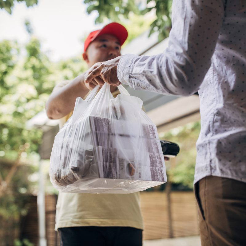A delivery man bringing food to a male customer.