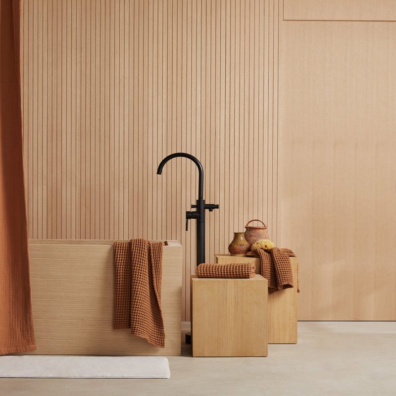 A Parachute shower curtain, a bathtub, and towels evoking an earthy vibe.
