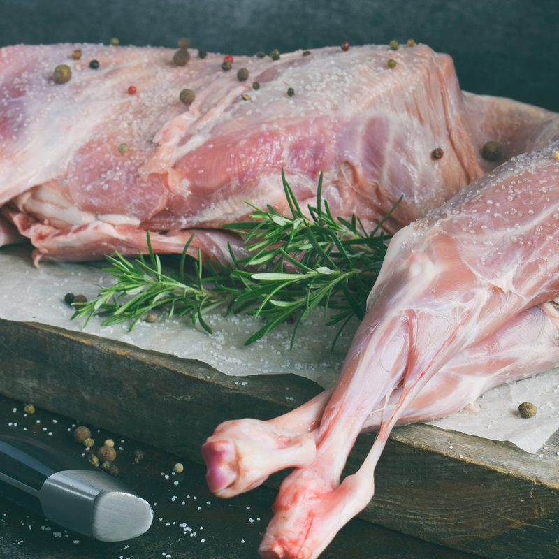 Whole raw lamb and knife on the wooden board.