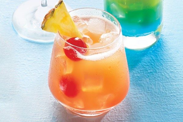 Rum swizzle garnished with pineapple and cherry.
