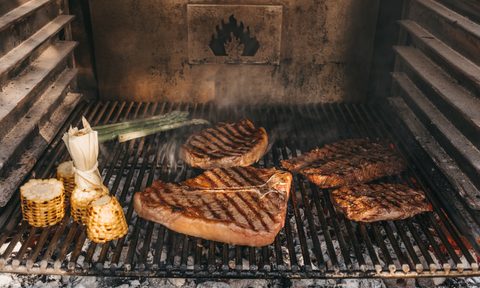 Steaks on grill with corn.