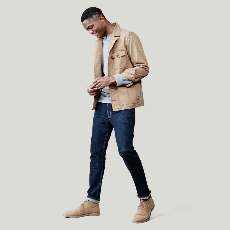 A smiling male model in smart casual attire looking at his shoes.