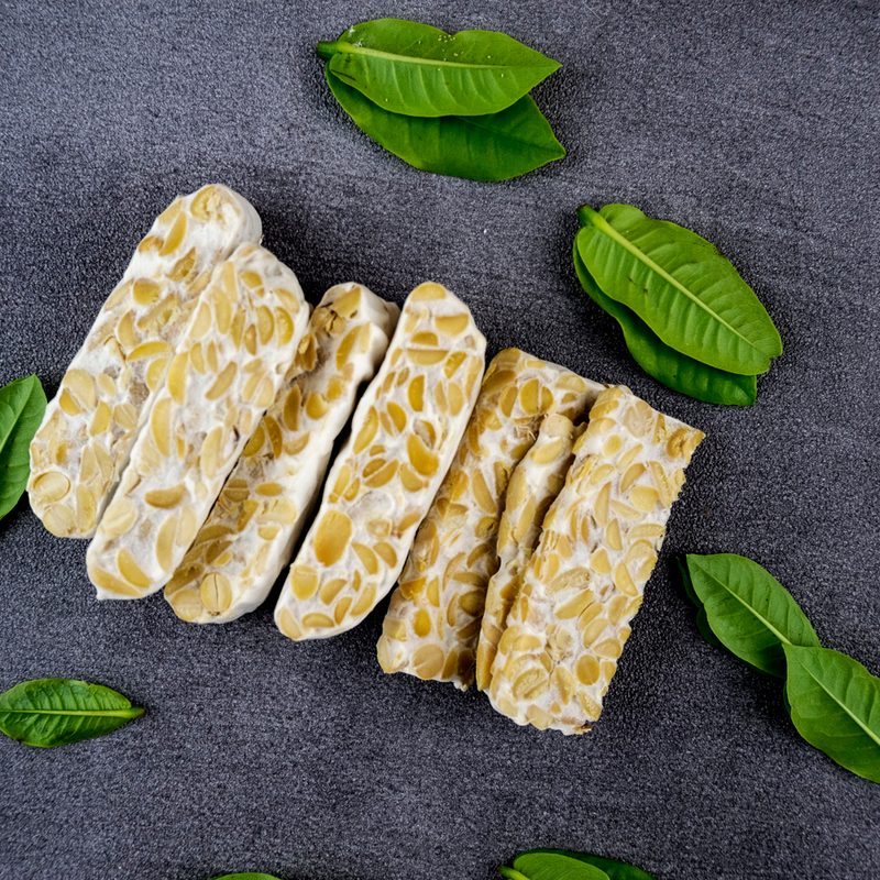 Tempeh slices with leaves on a table.