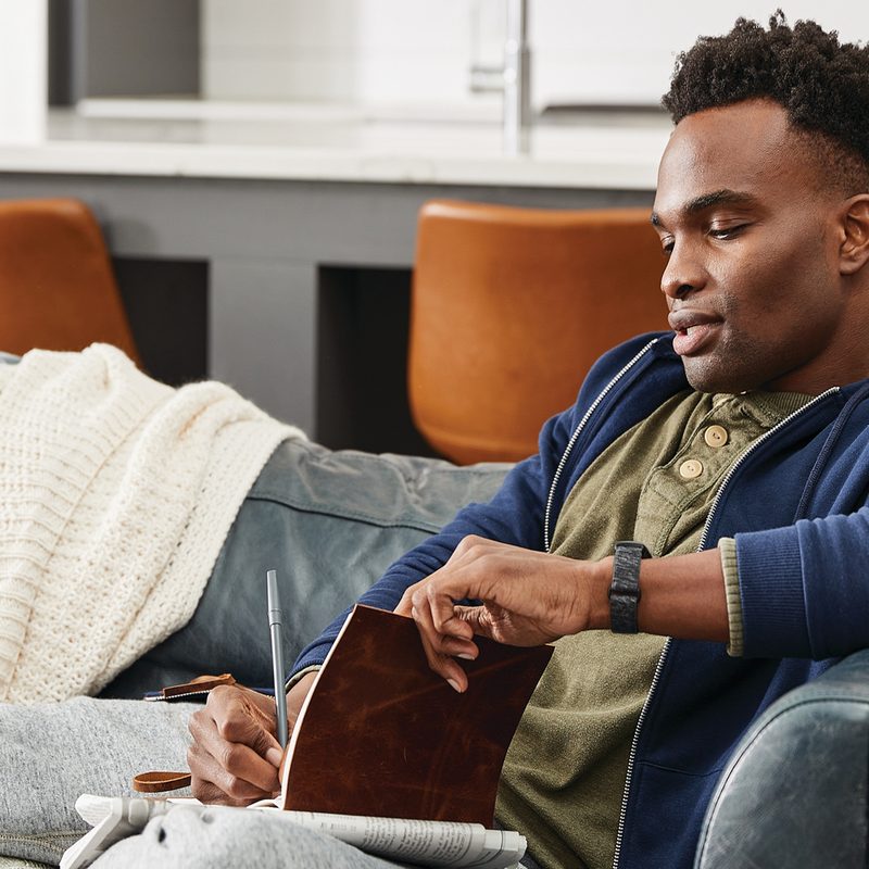 A man on sofa writing in his journal.