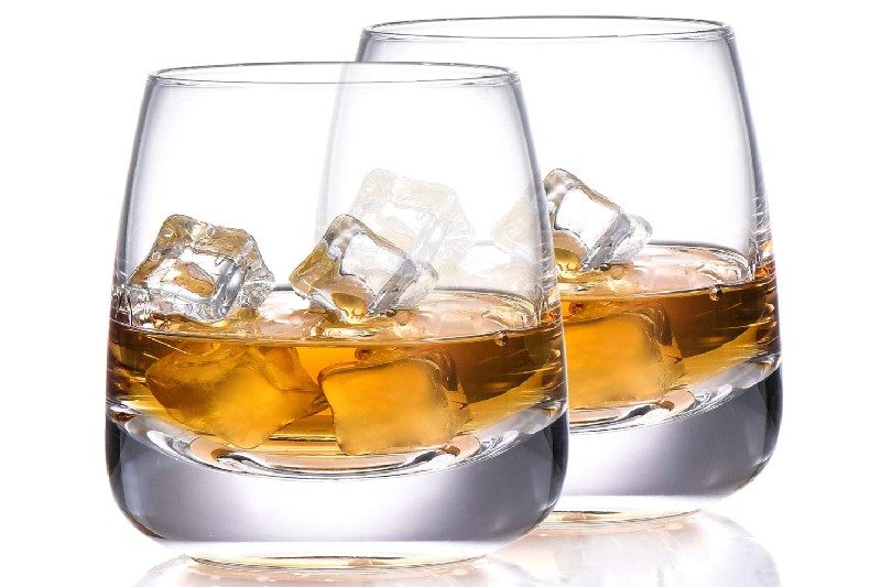 Two tumbler glasses with whiskey in them.