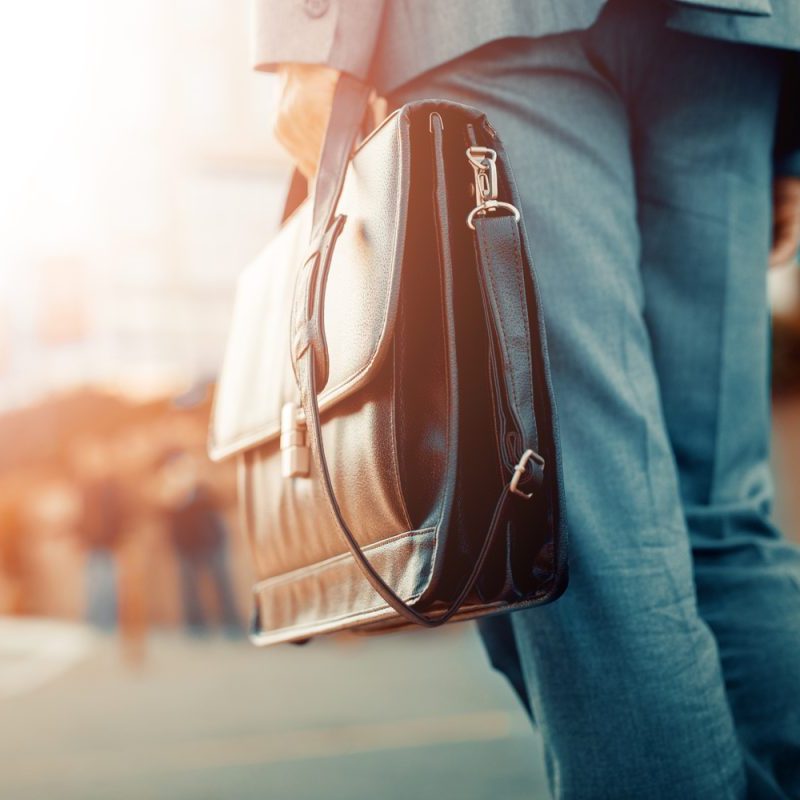 A man in business attire carrying a briefcase to work.