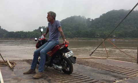 Anthony Bourdain sitting on a motorcycle looking off into the distance.