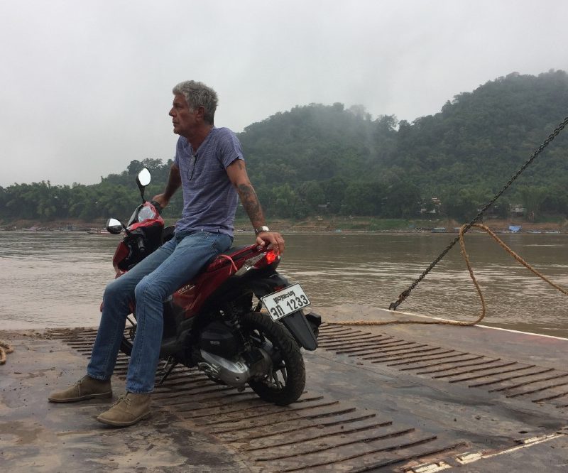 Anthony Bourdain sitting on a motorcycle looking off into the distance.