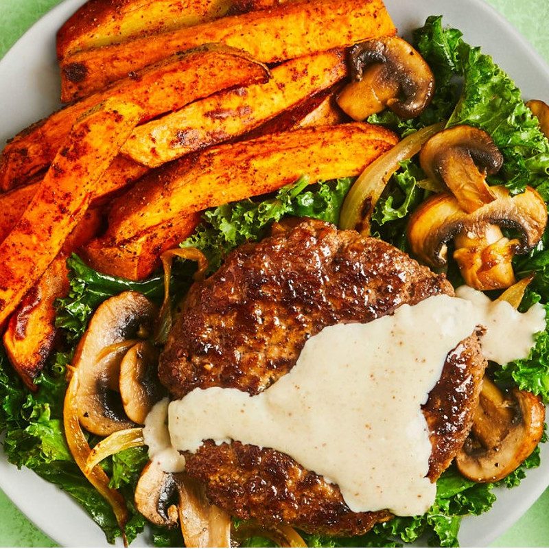 cooked beef patties with kale and sweet potato fries.