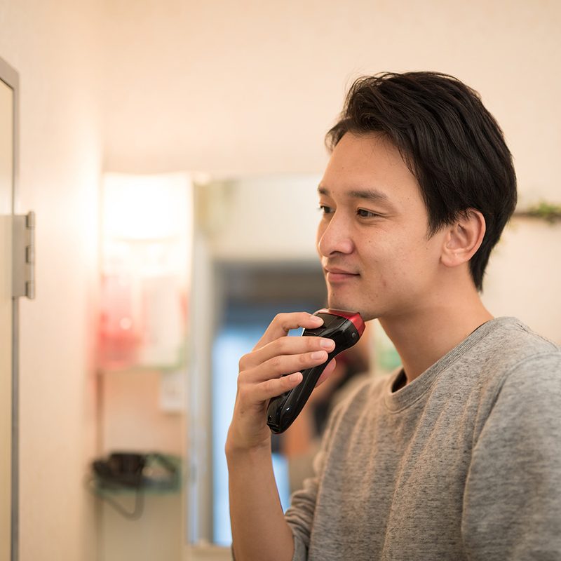 Man shaving with electric razor.
