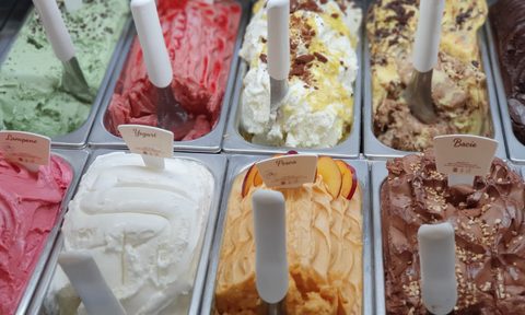 pans of different flavored ice cream with scoops in each one.