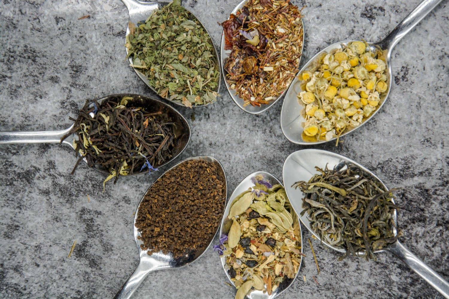 Spoons of different tea leaves.
