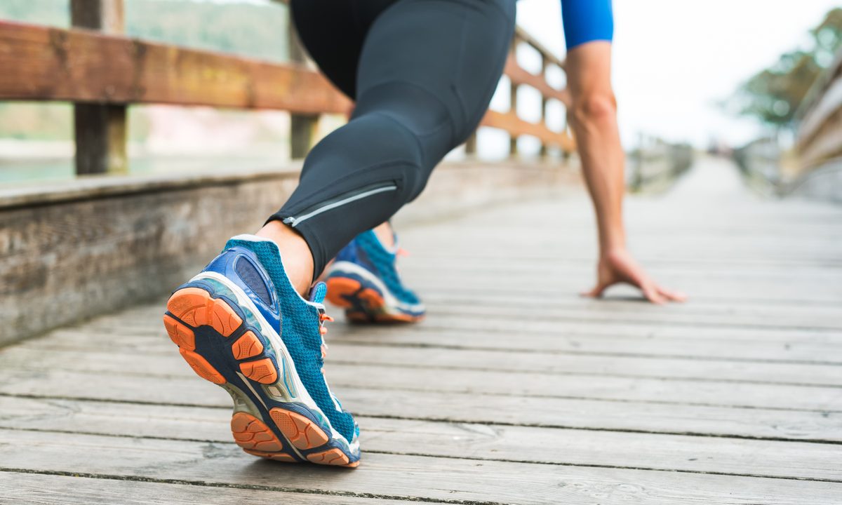 Fitness man ready for running on wooden walkway on park.