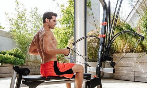 Man using the Bowflex Home Gym in an outdoor enclosed patio area.