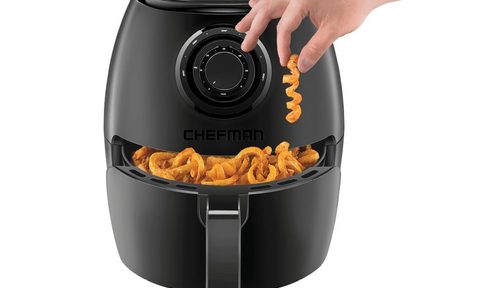 Chefman Turbofry Air Fryer full of curly fries with a hand picking one up, on a white background.