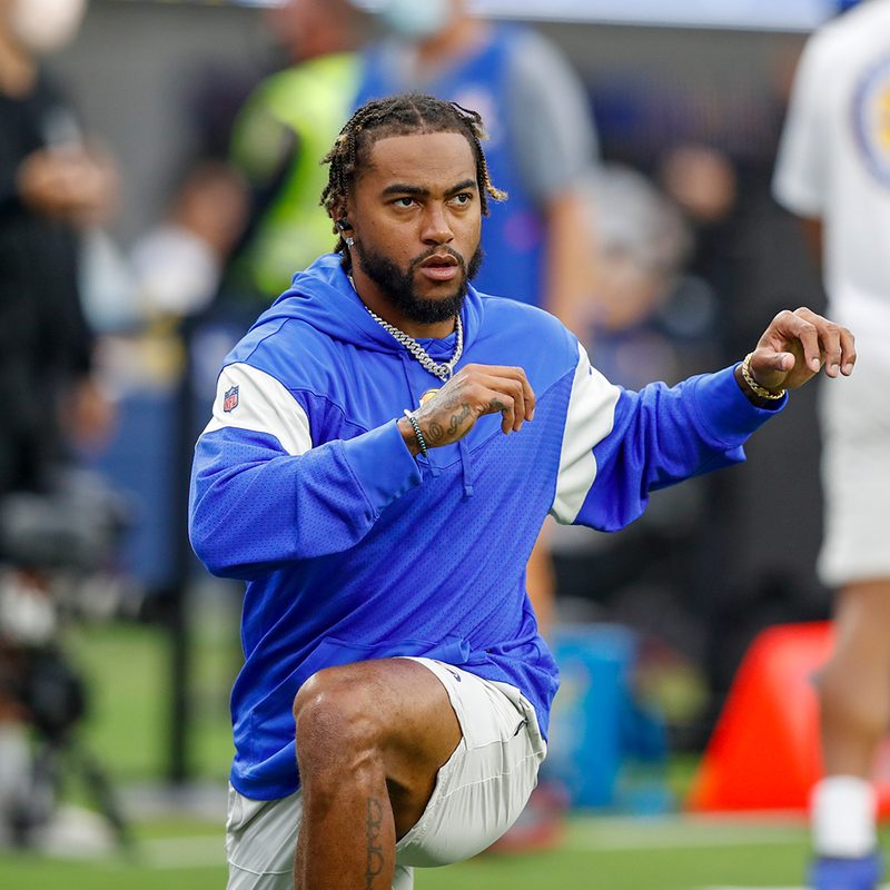 DeSean Jackson in shorts and blue hoodie doing stretches on the field.