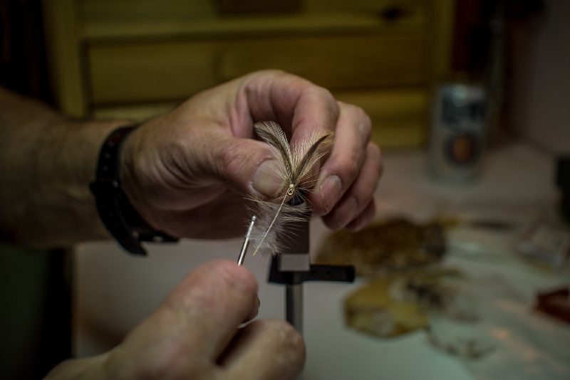 pair of hands working on a fly tying technique.