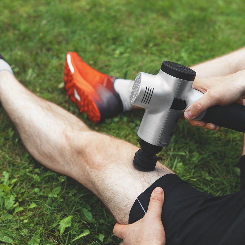 Man massaging leg with massage percussion device after workout.