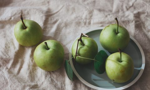 Granny Smith apples in a bowl on a table.