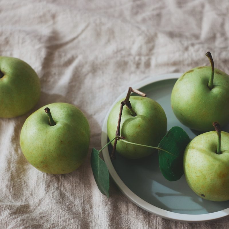 Granny Smith apples in a bowl on a table.