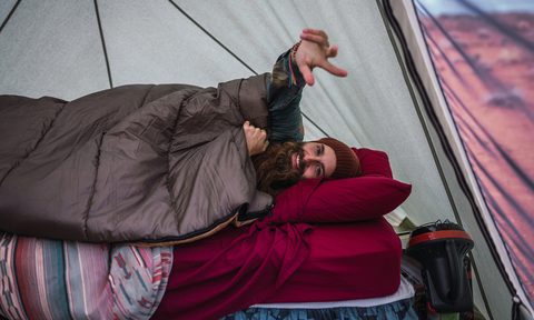 Cheerful traveler lying on a mattress in a tent.