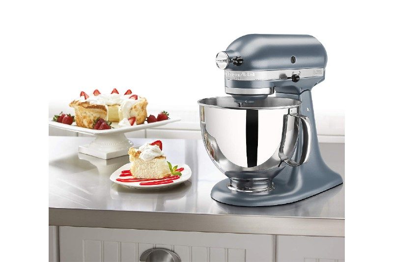 kitchenaid artisan series mixer sitting on the counter next to a slice of cake.