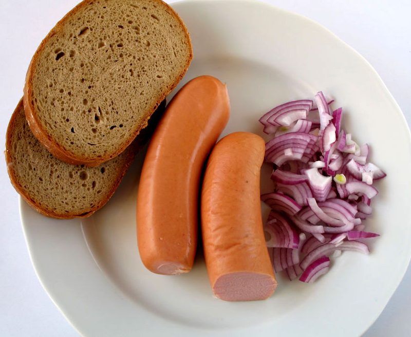 Knackwurst sausage on a plate with cabbage and bread.