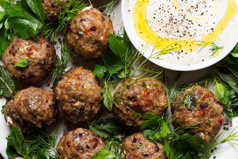 A plate of feta lamb meatballs with creamy sauce.