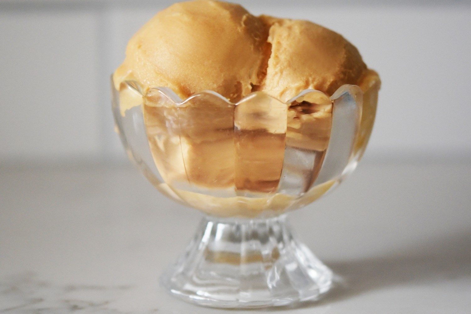 ninja creami lite apple pie ice cream scoops in a clear glass dish.