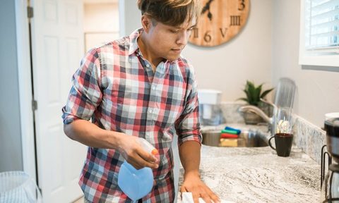 Man cleaning kitchen with spray bottle before holidays.