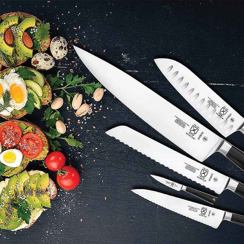 Five Mercer knives beside various healthy foods on a table.